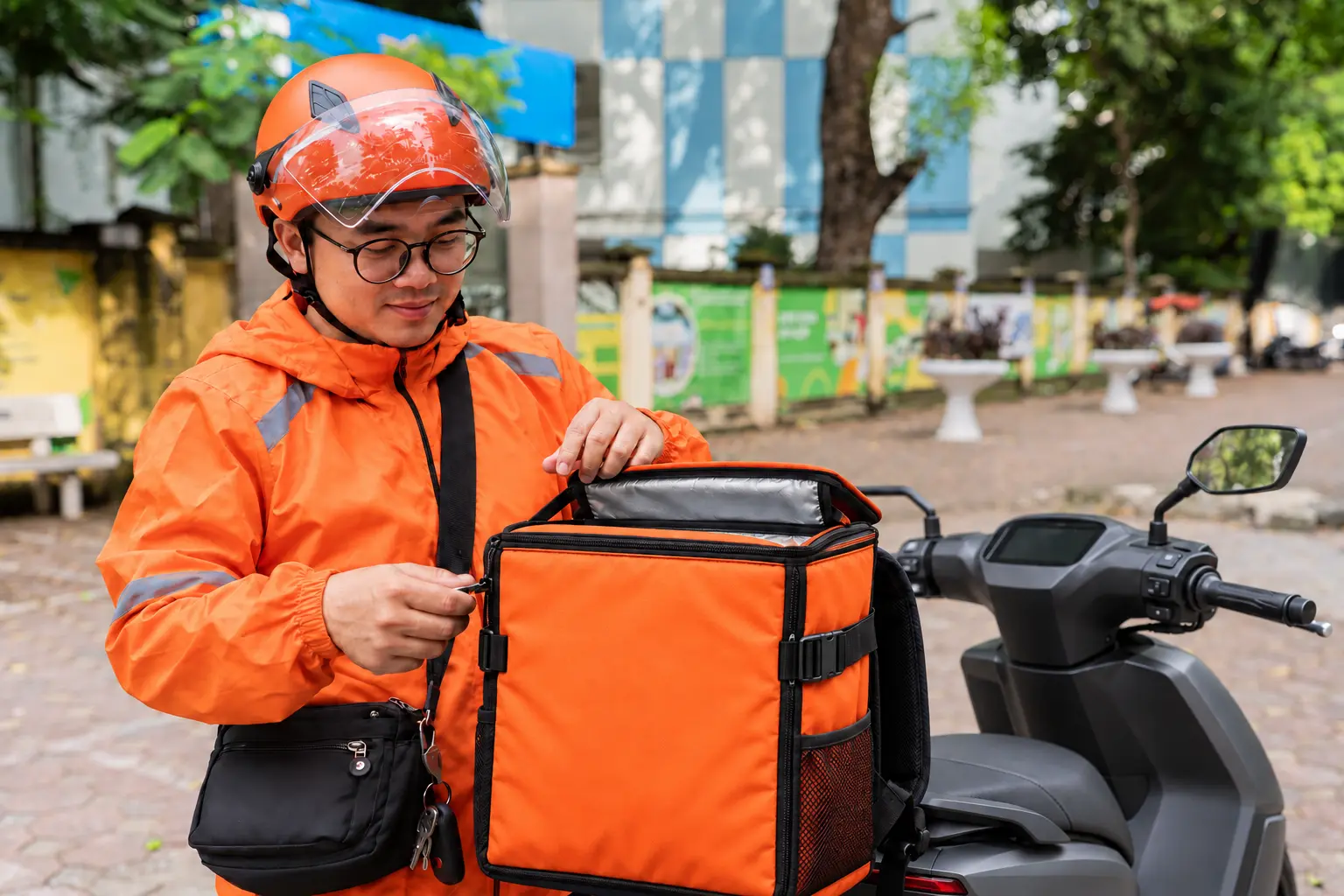 Tài xế đang chuẩn bị túi giao hàng bên cạnh xe máy